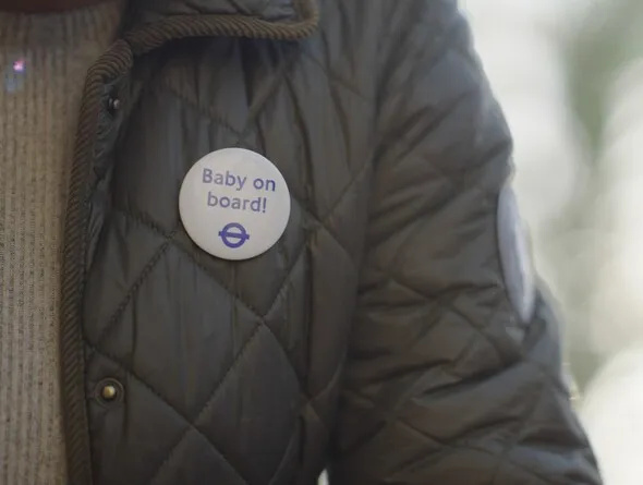 Close-up of a woman's upper torso with baby on board badge pinned to her jacket