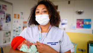 A maternity support worker holding a baby