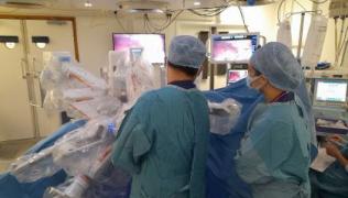 Surgeons in greens scrubs are in an operating theatre, using the new robot system