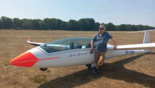 Bert standing next to his air glider in an open field