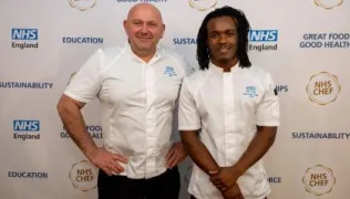 Chef Ned and Chef Joe in chef whites, standing in front of a backdrop with NHS England and other logos