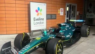 A green Aston Martin Formula One car parked outside of the Evelina London Children's Hospital main entrance