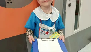 Luna dressed as a nurse holding a clipboard in Evelina London Children's Hospital. 