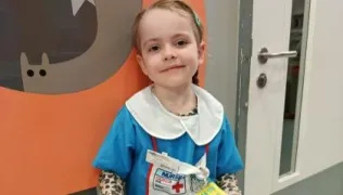 Luna dressed as a nurse holding a clipboard in Evelina London Children's Hospital. 