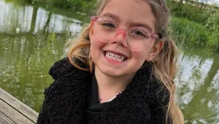 Paisley Rose standing outside in coat after discharge from Evelina London Children's Hospital 