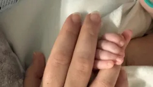 Atlas's finger holding onto Tansy's with a ring on it. 