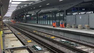 An empty track and people in orange hi-vis jackets at Waterloo East station
