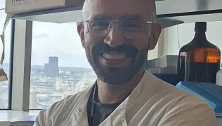 Dr Ferreira wearing a white lab coat smiling at the camera