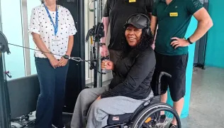 A patient in a wheelchair with physiotherapy staff in a community gym 