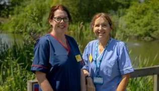Emma and Charis standing together in front of a lake
