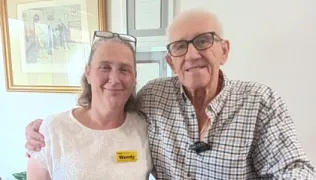 A patient and his rehabilitation support worker standing in their home