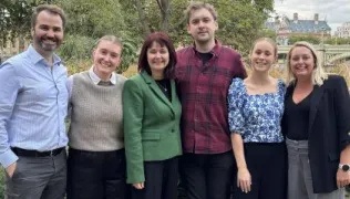 Six members of the two trusts' Epic team stand smiling in a garden area near the Thames riverbank.