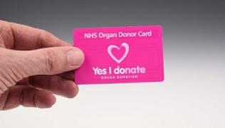 A hand holding an NHS organ donor card