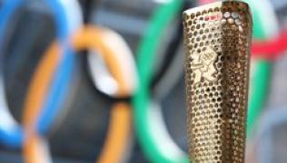 Close-up of the Olympic Torch with out of focus Olympic rings in the background
