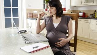 A pregnant woman looking at a laptop