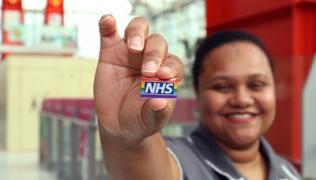 Healthcare worker holding up NHS rainbow badge
