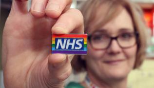Healthcare staff member holding up a rainbow badge
