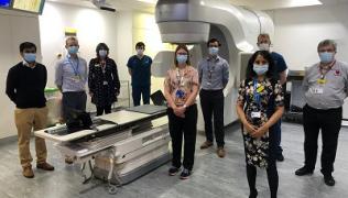 Team of clinicians next to radiotherapy machine