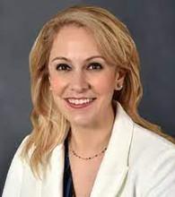 Julia Grapsa has blonde hair and is wearing a white blazer