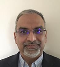 Prathap Pillai is a man with very short grey hair, glasses, and a short grey beard