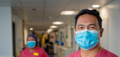 A nurse in scrubs wearing a face mask 