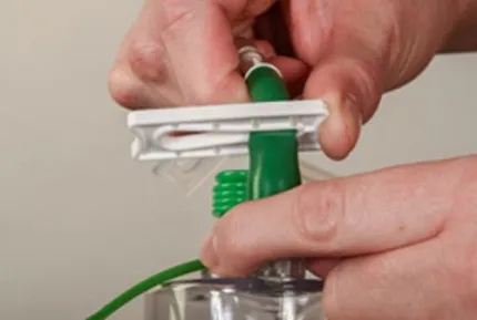 A close-up of hands sliding the plastic clip tube coming from the bottle, so the narrow side is clipping the tube closed