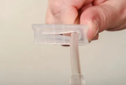 A close-up of a hand sliding the plastic clip so the open side is around the tube.