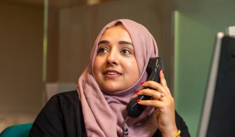 A member of staff wearing a headscarf using a telephone