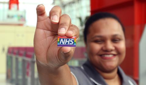 Nurse holding an NHS rainbow badge