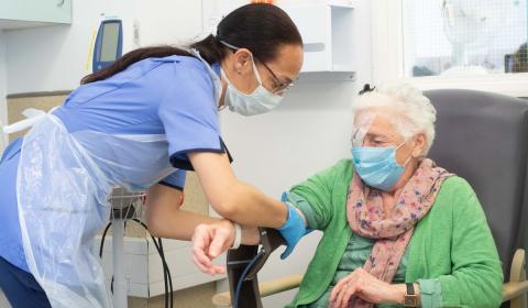 A nurse taking the blood pressure of an older patient 