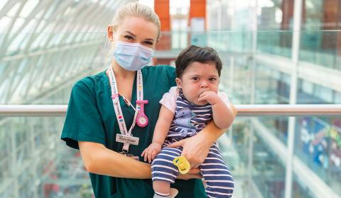 Nurse wearing a face mask holding a baby 