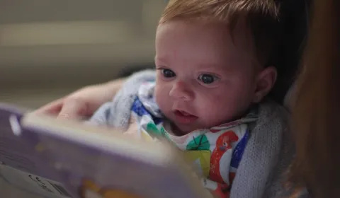 A close-up of a 3-month-old baby being read a story.