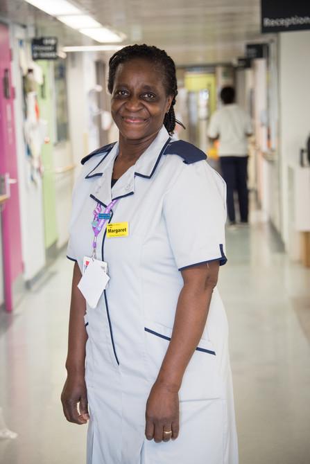 Advanced nursing assistant on a ward wearing a light grey uniform.