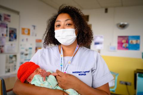 A maternity support worker holding a newborn baby