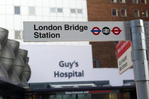 London Bridge station direction sign with Guy's Hospital main entrance and sign in background