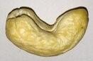 Image of one whole cashew on a flat surface. 