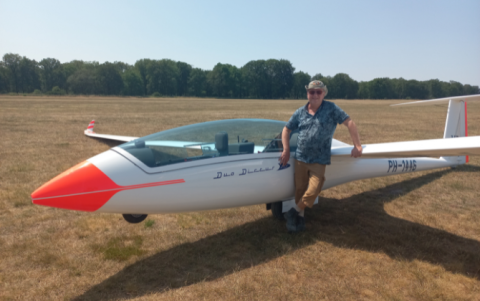 Bert standing next to his air glider in an open field