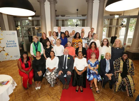 A group of people seated and standing. Next to them is a banner marked 'Long Service Awards'