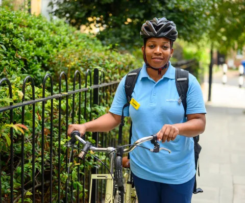 Luria, a community staff nurse and part of neighbourhood nursing team, standing next to bike outside on way to patient home