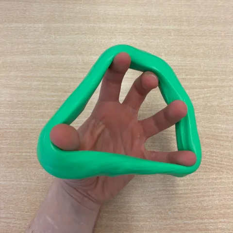 Photo of someone's hand with a large ring of green putty around their fingers and thumb. They have spread out their fingers widely.