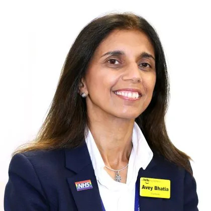 Headshot of Avey, wearing a navy jacket and white shirt. She has long, dark hair and is smiling into the camera.