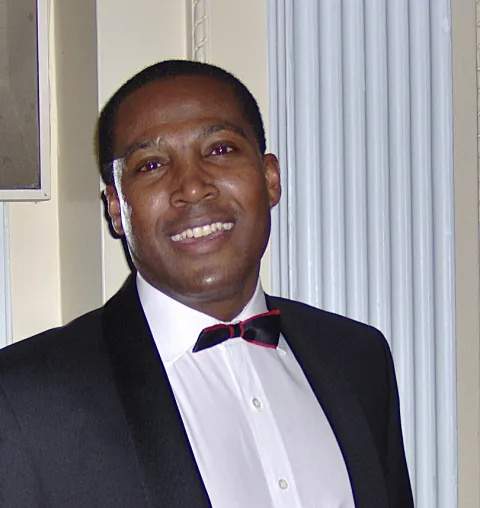 A man wears a black jacket, white shirt and black bow tie