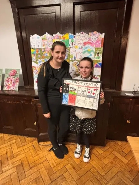 Lilah and her mum, Daisy, together at the auction with Lily holding her art work up. 