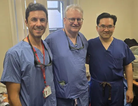 Three surgeons wearing blue scrubs are standing next to each other