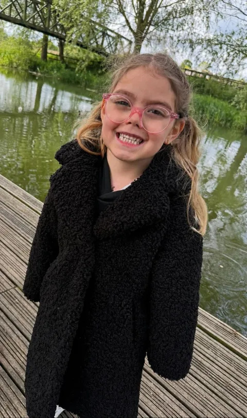 Paisley Rose standing outside in coat after discharge from Evelina London Children's Hospital 