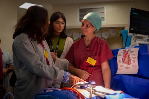 Alina Biris, theatres scrub practitioner, demonstrating a cardiac procedure to two Open Day attendees