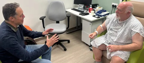 Patient and BBC journalist speaking in hospital room. 