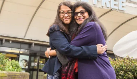 Prafula, in a purple coat, is hugging her niece Shakti, side-by-side and facing the camera. They are outside Royal Free Hospital