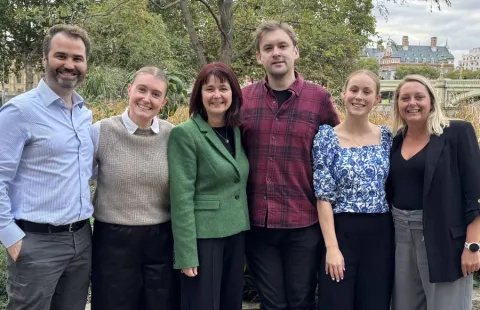 Six members of the two trusts' Epic team stand smiling in a garden area near the Thames riverbank.