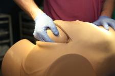Practising emergency caesareans using Desperate Debra, a new caesarean simulator (close up of removing baby's head from abdomen)